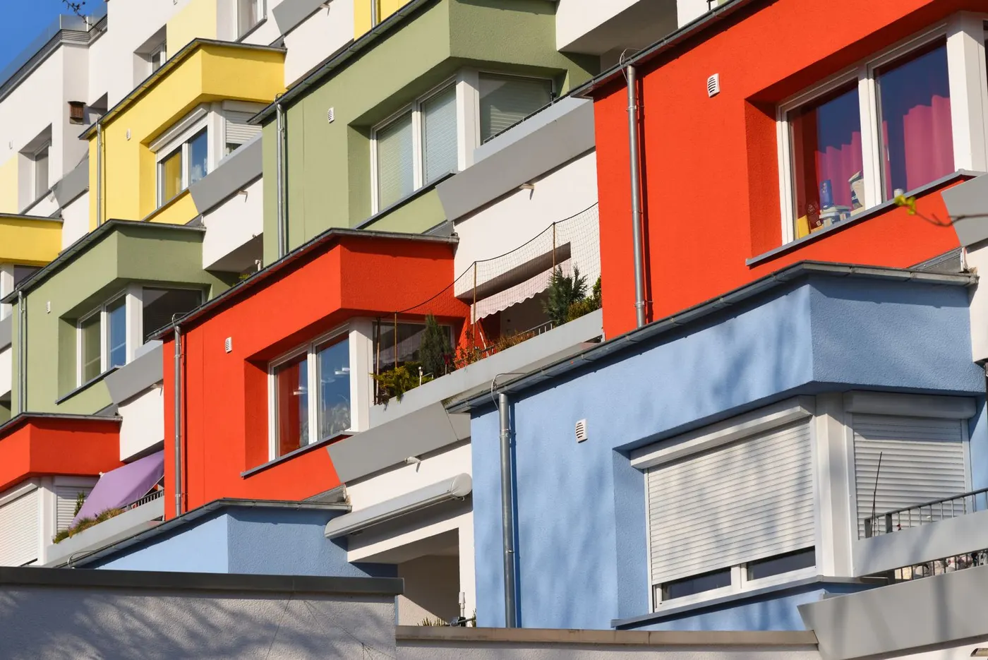 Fassade eines Mehrfamilienhauses mit Erkern in Rot, Blau, Grün und Gelb