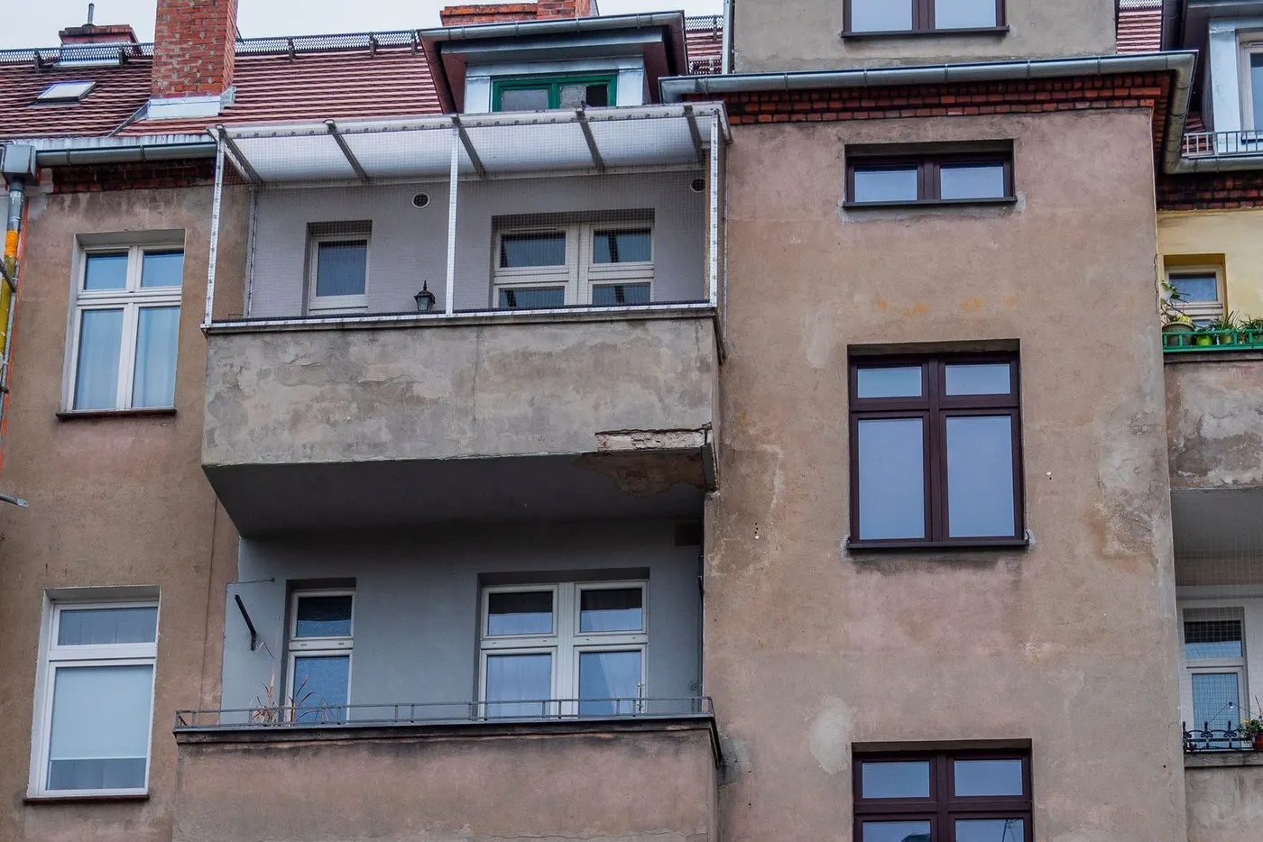 Unsanierte Putzfassade eines älteren Mehrfamilienhauses mit Balkonen